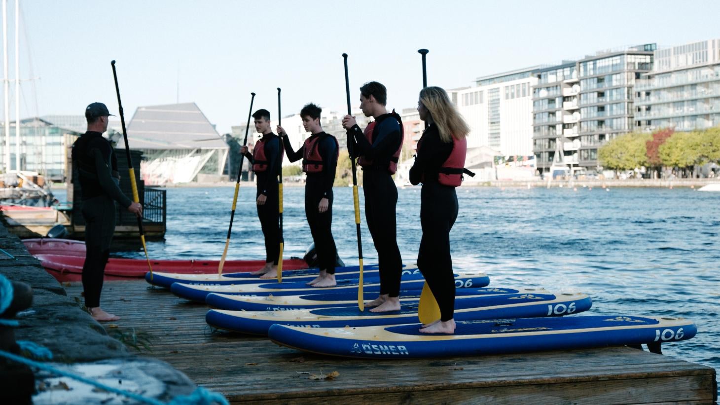 People standing on paddle boards at Grand Canal Dock in Dublin.