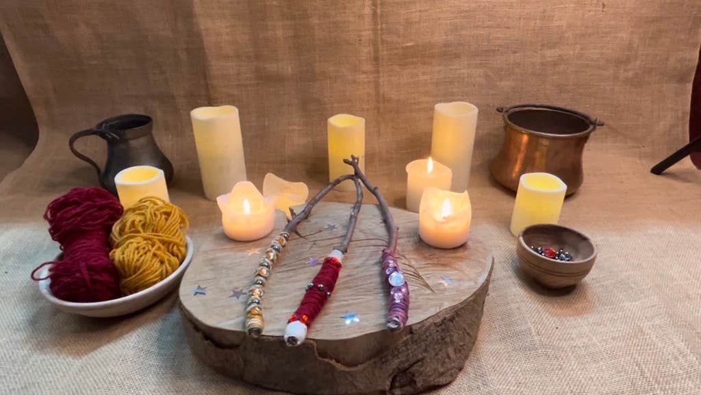 decorative wands sit on a wooden wedge with a hessian backdrop surrounded by candles