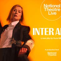 A woman in dark suit and white shirt is moving, slightly blurred, against orange background.