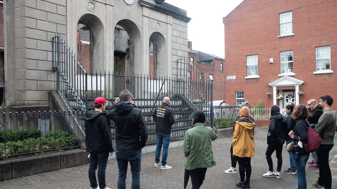 Group on a walking tour with the Coombe hospital monument in the background