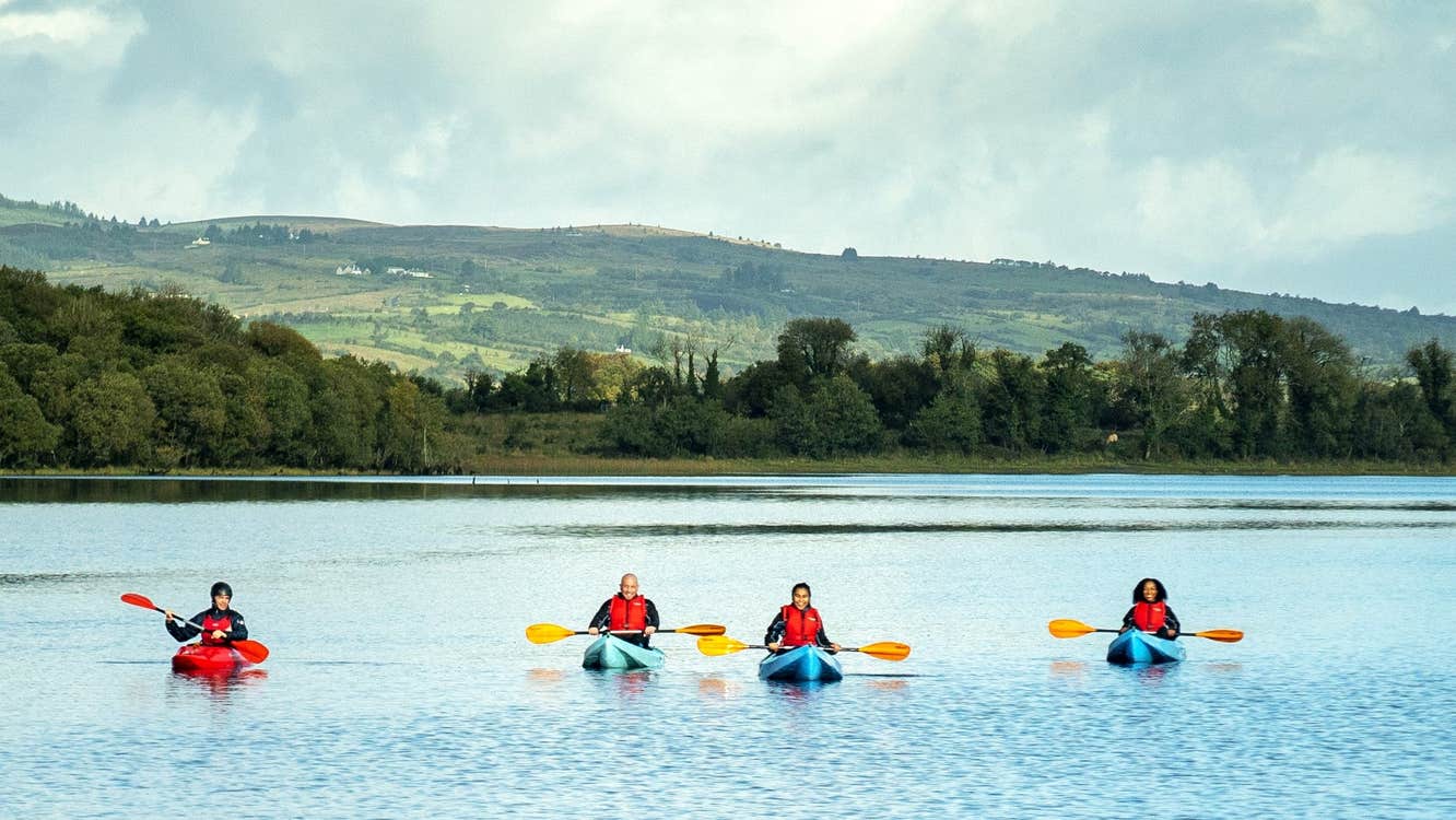 A group out kayaking in the water with the beautiful green landscape in the background