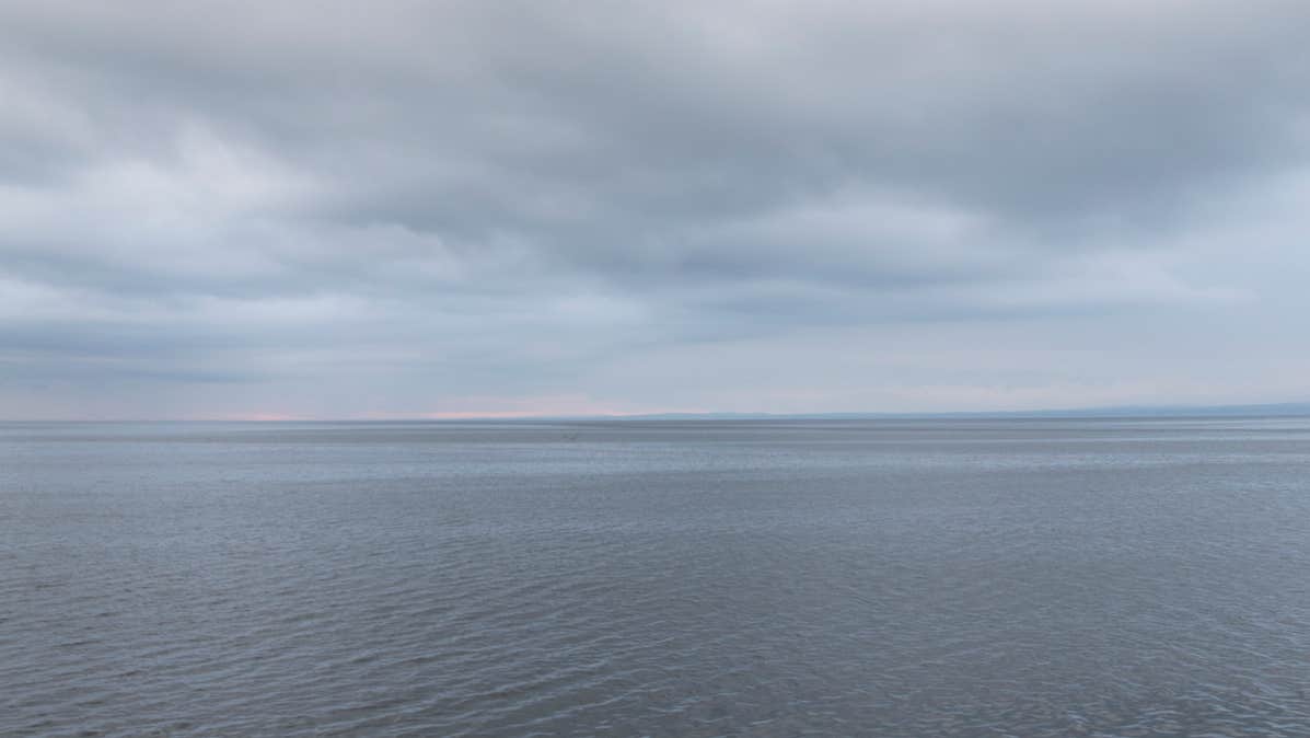 Richie Stokes, The Flaggy Shore, a view across a large open calm expanse of water with cloudy sky