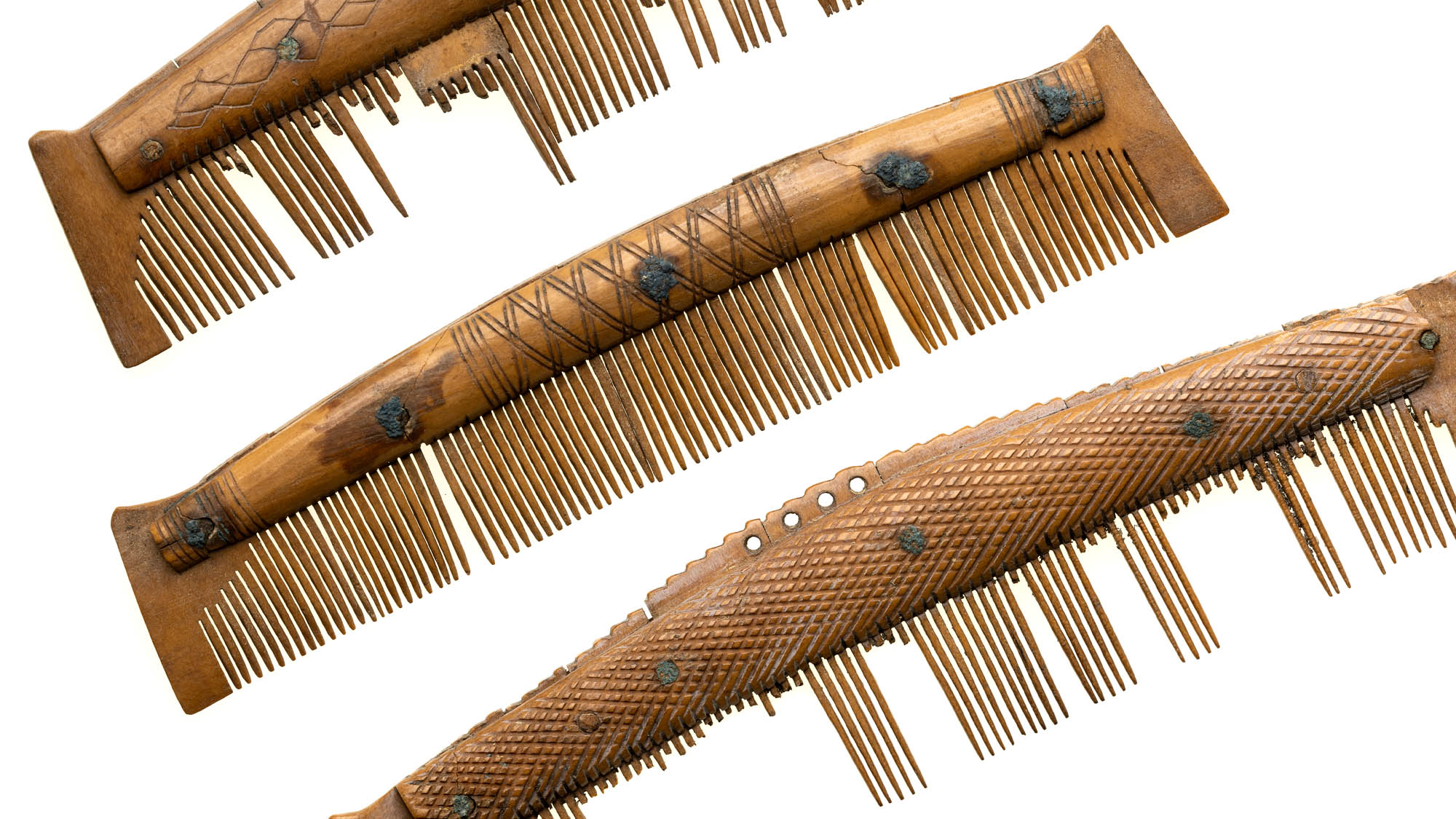 3 old brown combs with many teeth missing, against plain white background.