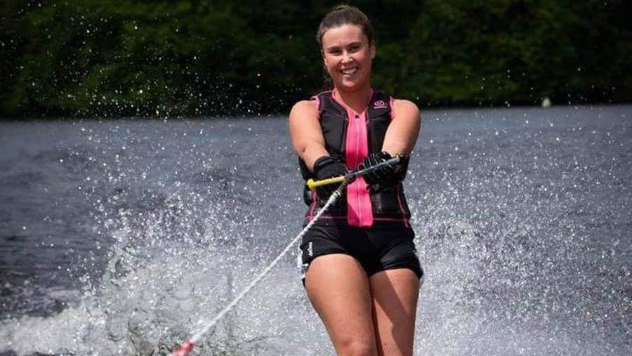 A woman smiling into the camera as she water skis