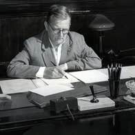 Composer Dmitri Shostakovich - black and white old photo of a man seated at a desk, writing