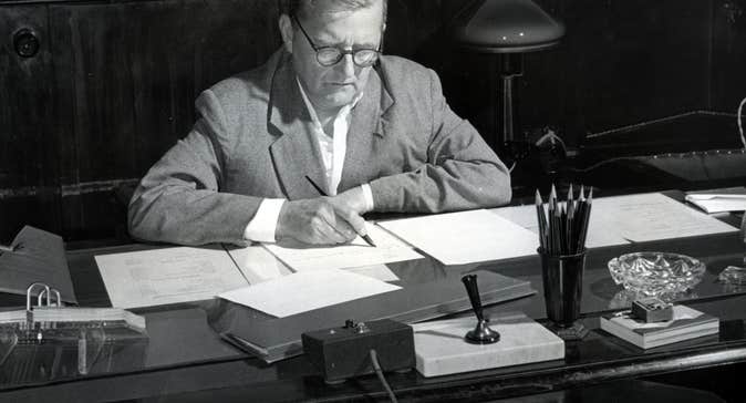 Composer Dmitri Shostakovich - black and white old photo of a man seated at a desk, writing