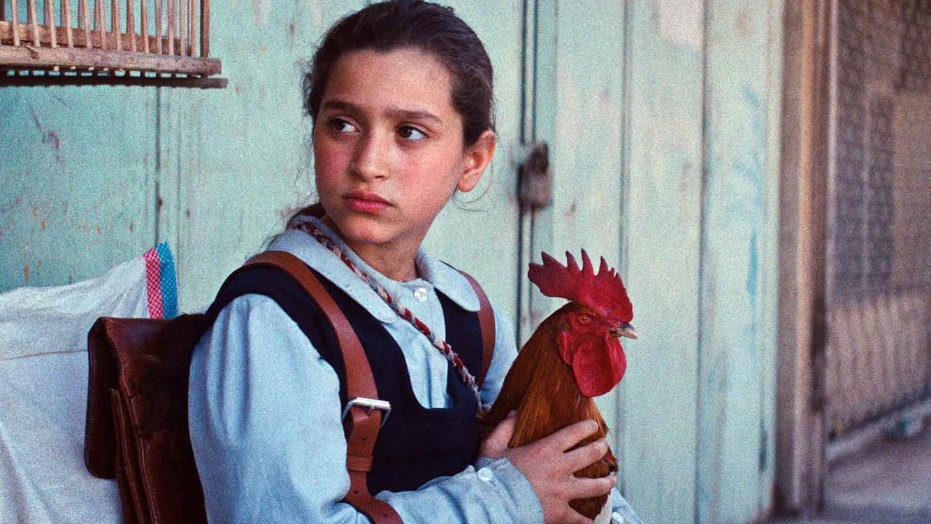 An anxious looking school girl is seated holding a chicken