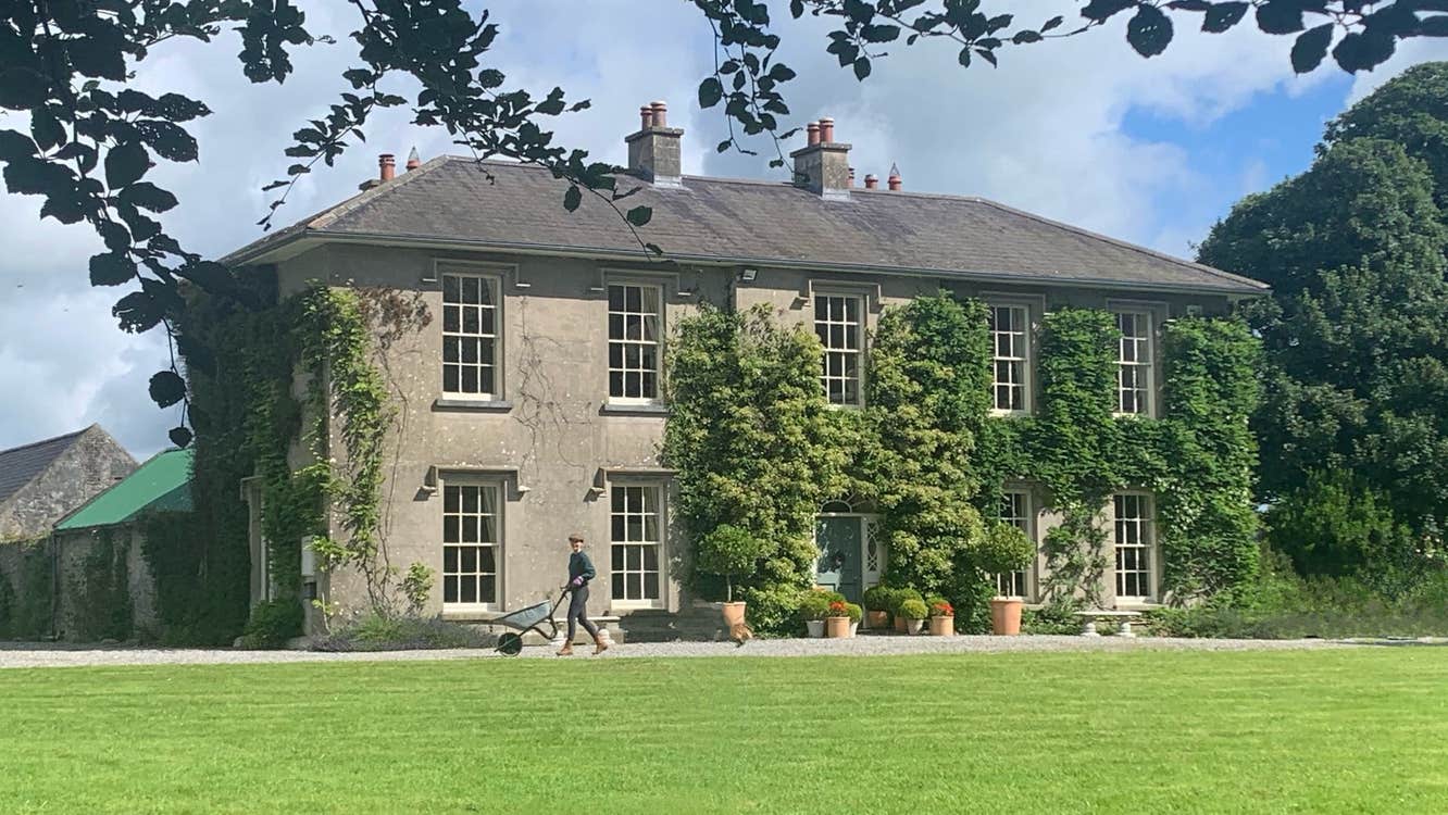 The exterior of a large country Georgian house with a lawn area to the front