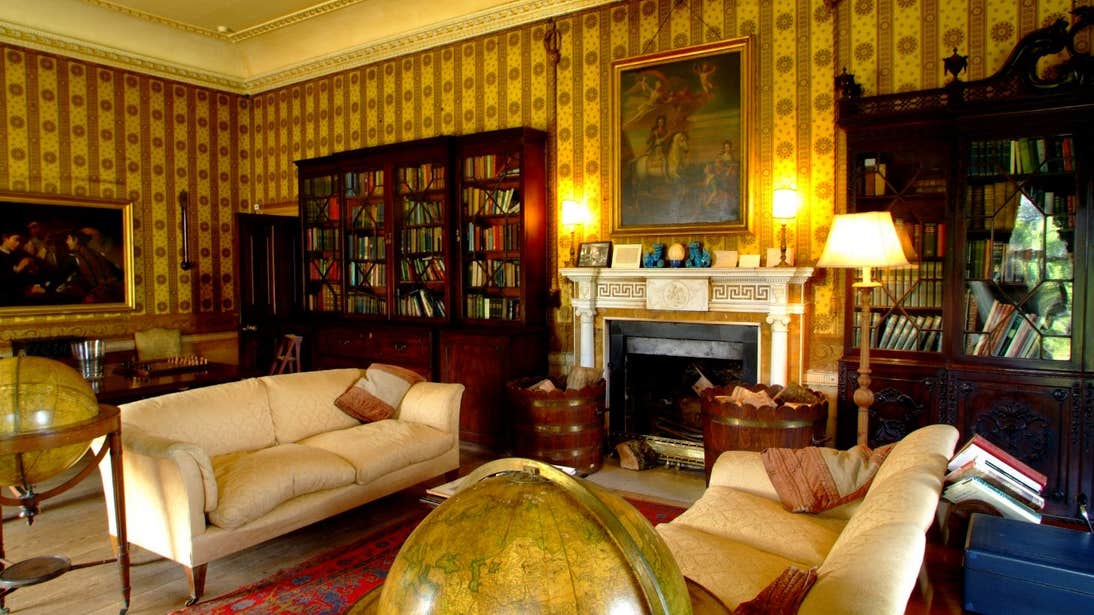 Paintings and books in a sitting room with white couches in Strokestown House, Roscommon