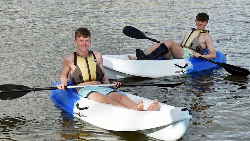 Two boys in kayaks on the water