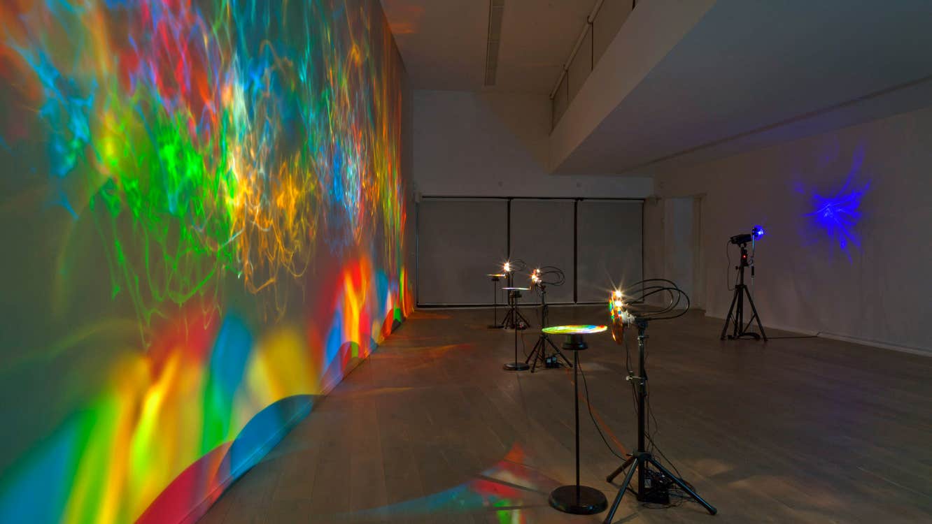 Colourful light show projected on a wall in a gallery
