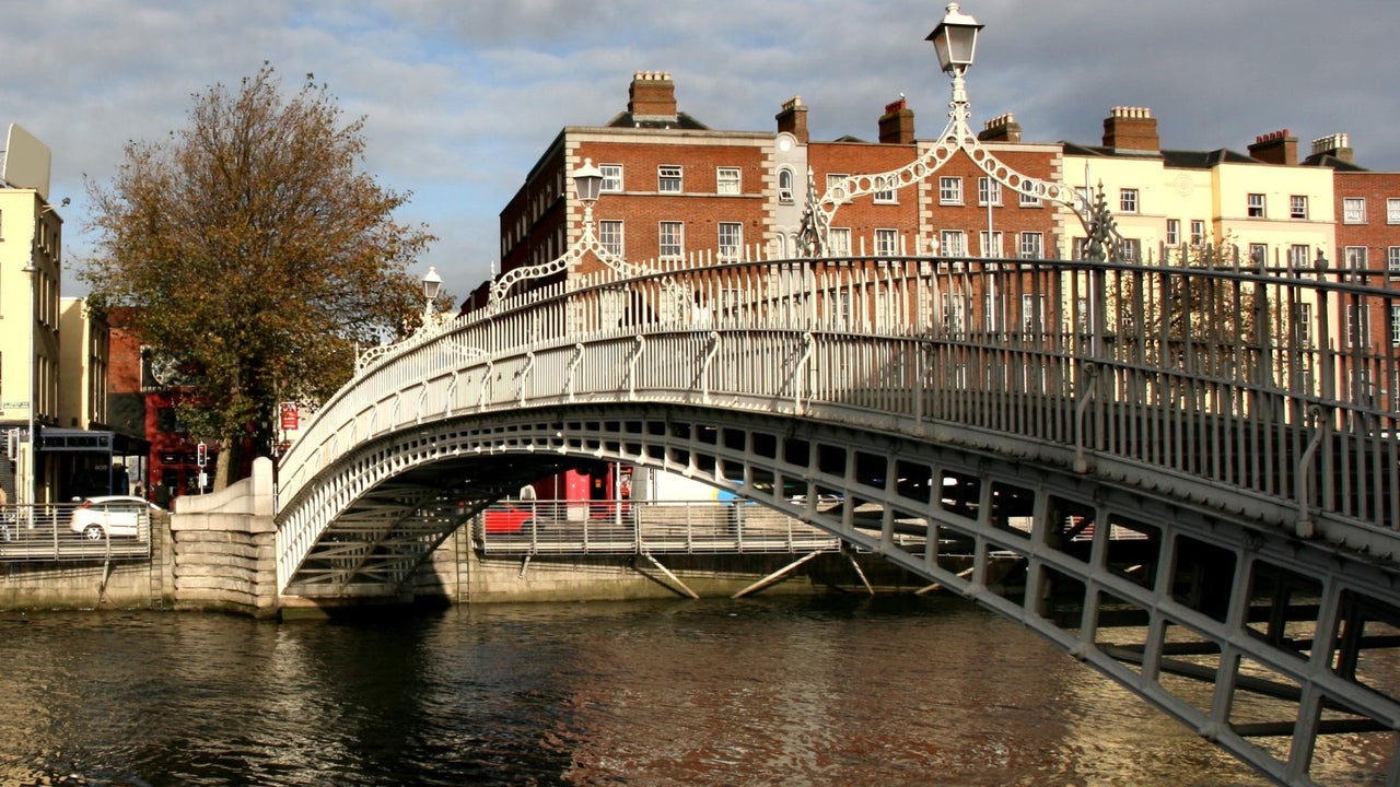Bridge over a river with a tree and red brick and cream buildings in the background