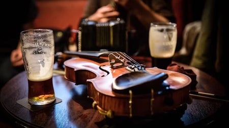Two nearly empty pint glasses on a pub table with a fiddle in the middle