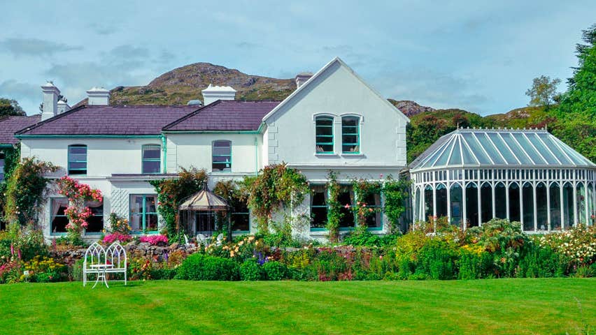 A front lawn flowers and shrubbery around the exterior of Cashel House Hotel
