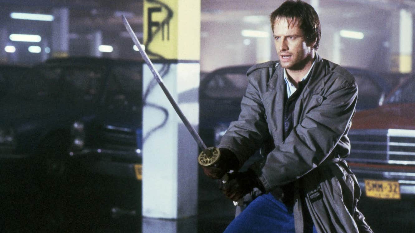 A man wielding a katana in a parking lot.