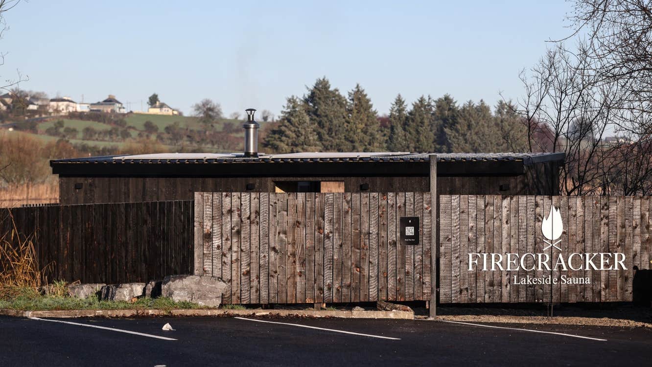 Wooden fencing around an outdoor sauna with trees in the background