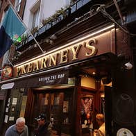 Outside of pub at dusk with two flags above a sign that reads P Kearneys