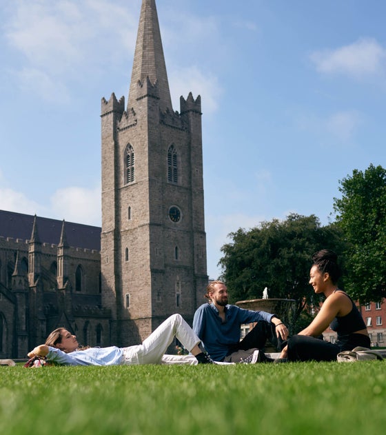People laying on the grass in front of St Patrick's Cathedral in Dublin city