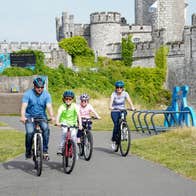 Two adults and two children cycling in front of a castle