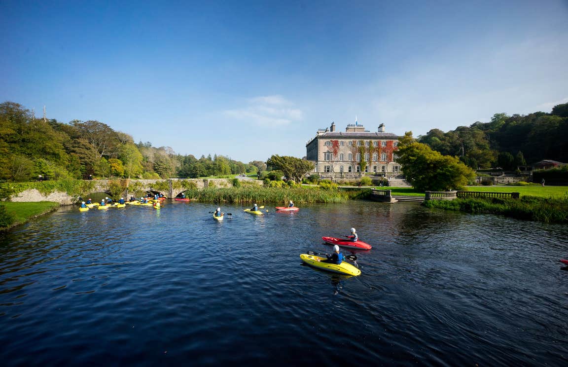 A group of people kayaking in front of Westport House, Mayo