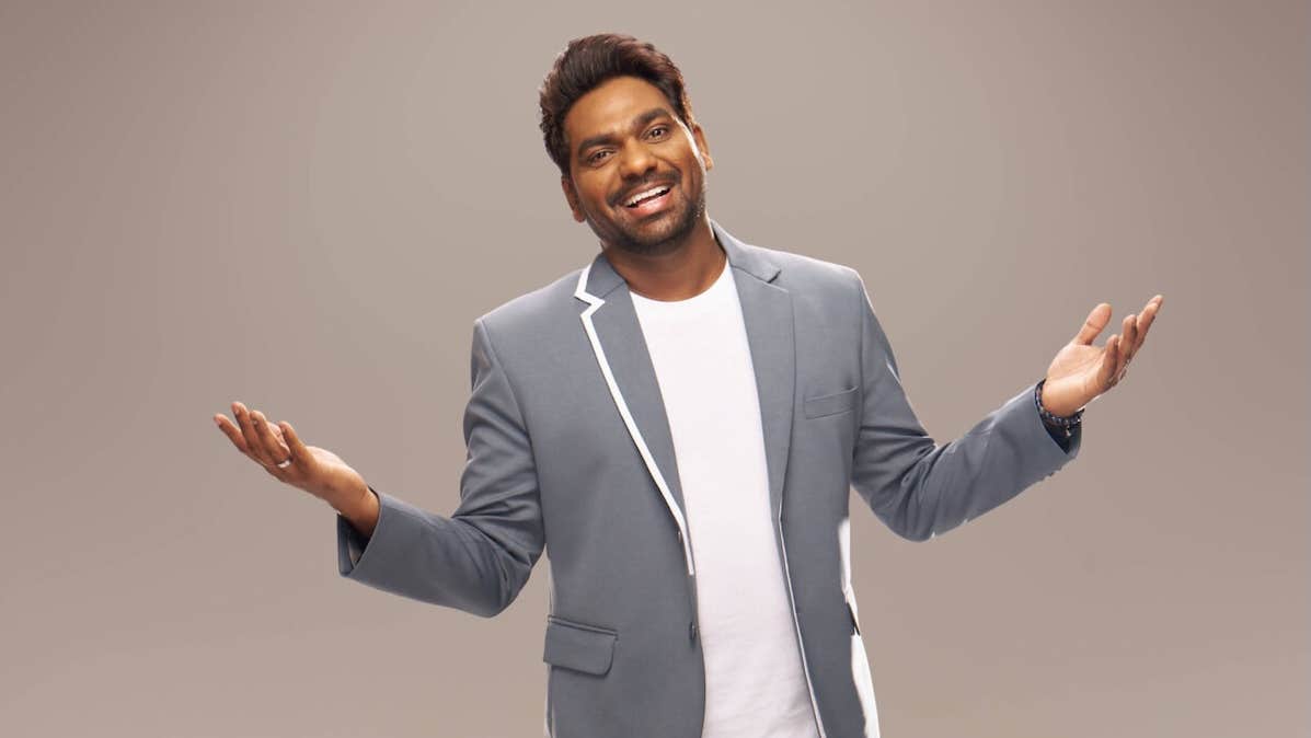 Indian global comedian Zakir Khan - a laughing man with arms open wide.