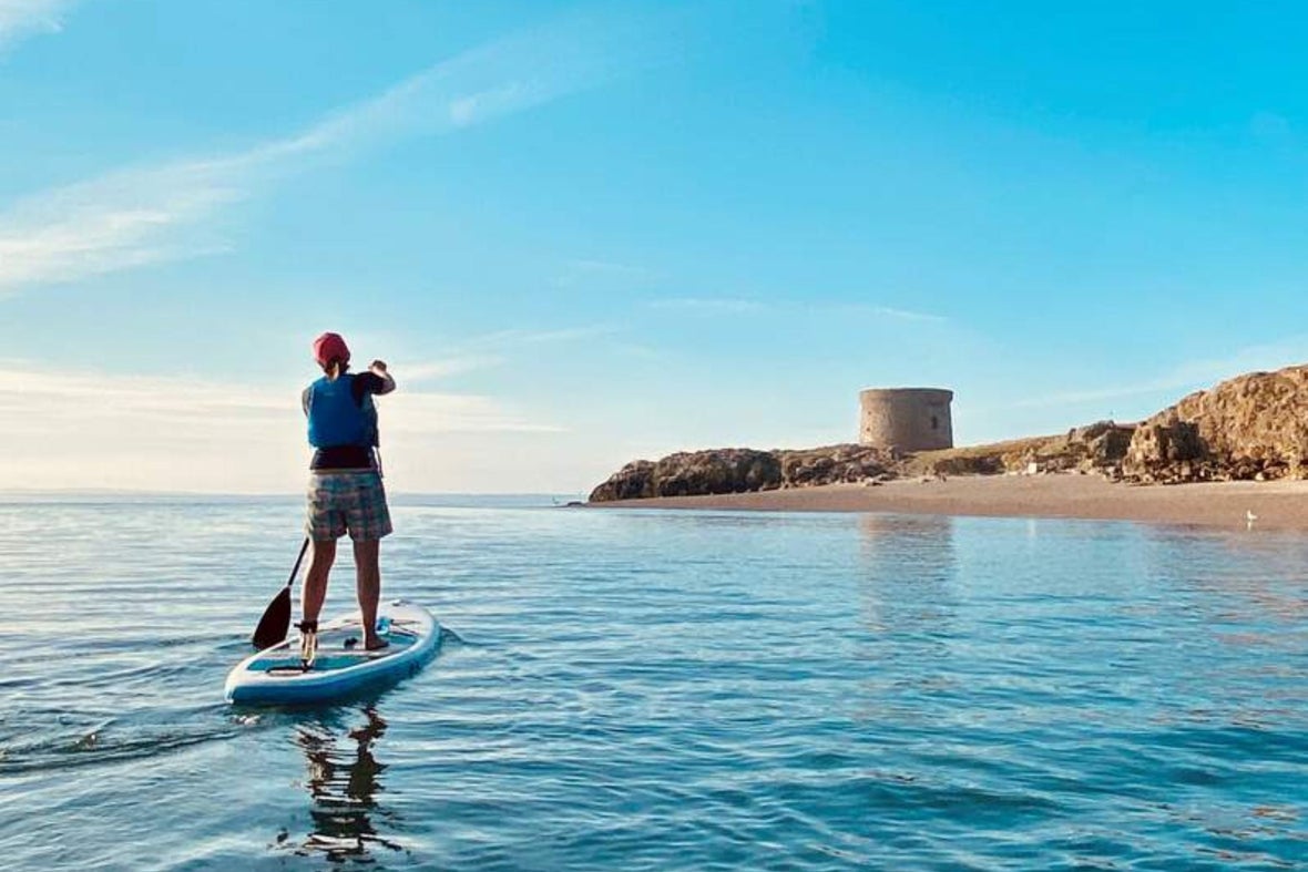 Person on a stand-up paddle board in the water at Dollymount, paddling.
