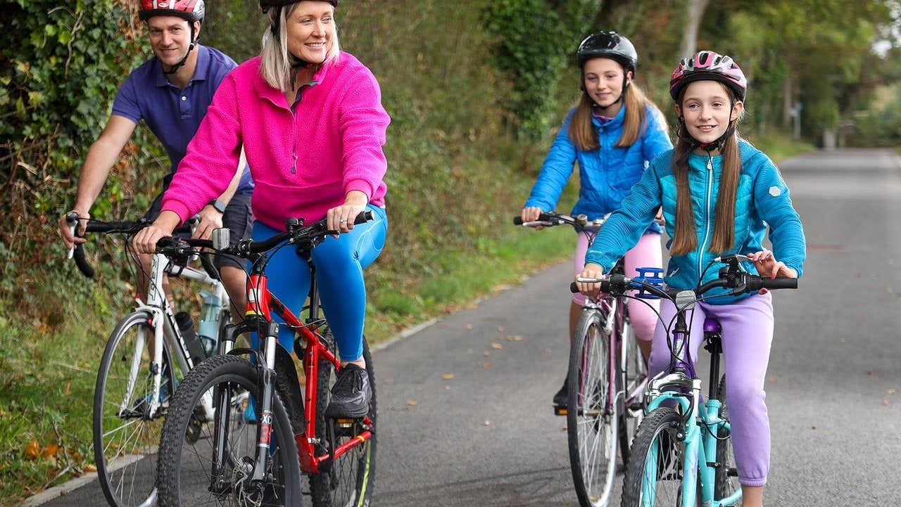 Two adults and two children on bicycles cycling along a greenway