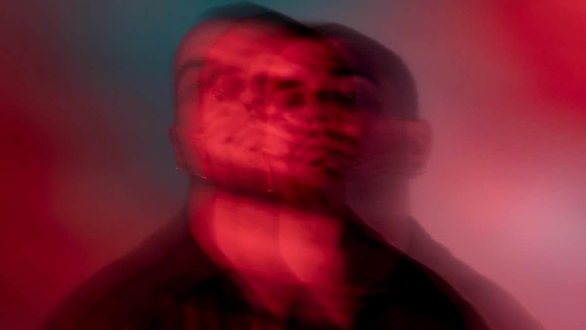 A very blurry headshot of a man in shades of red and black