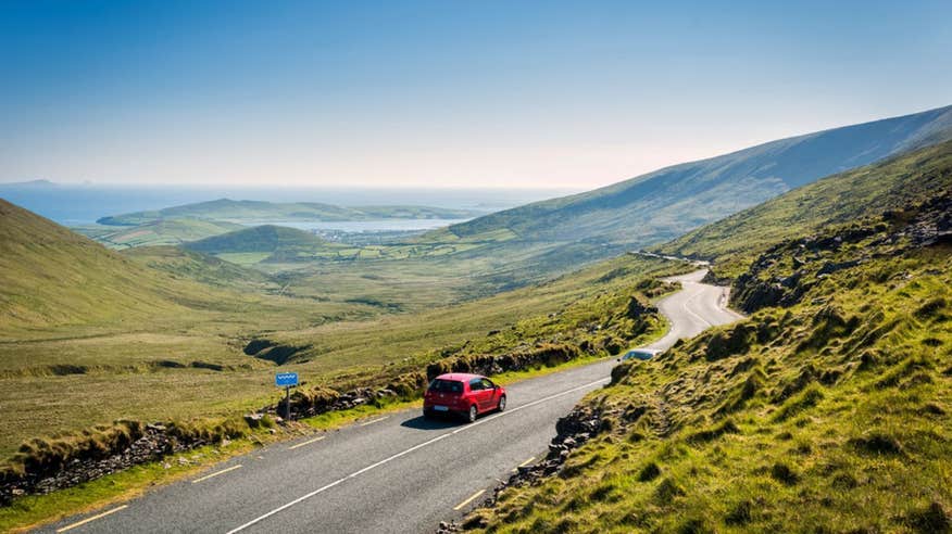 View of Conor Pass, Co. Kerry with a red car driving on the road