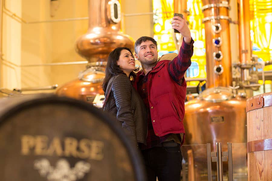 Pearse Lyons Distillery interior with couple taking selfies by the pot stills