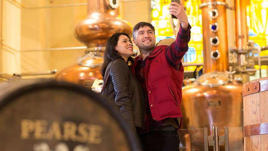 Pearse Lyons Distillery interior with couple taking selfies by the pot stills