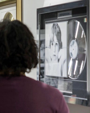 Image of two people viewing an assortment of platinum discs on the wall of fame