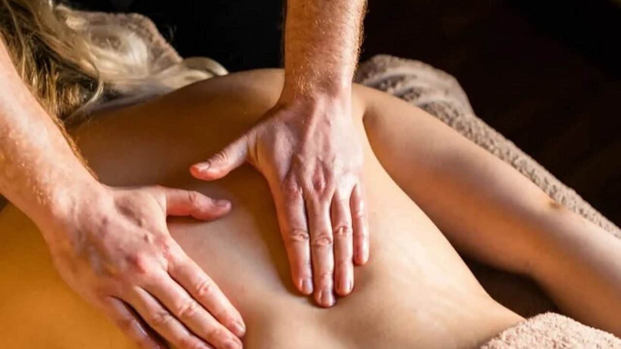 Massage therapist performing a back massage in a calm and relaxing therapy setting