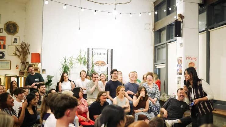 Seanchoíche Dublin in 2025, a woman holding a mic talking to a group of laughing people