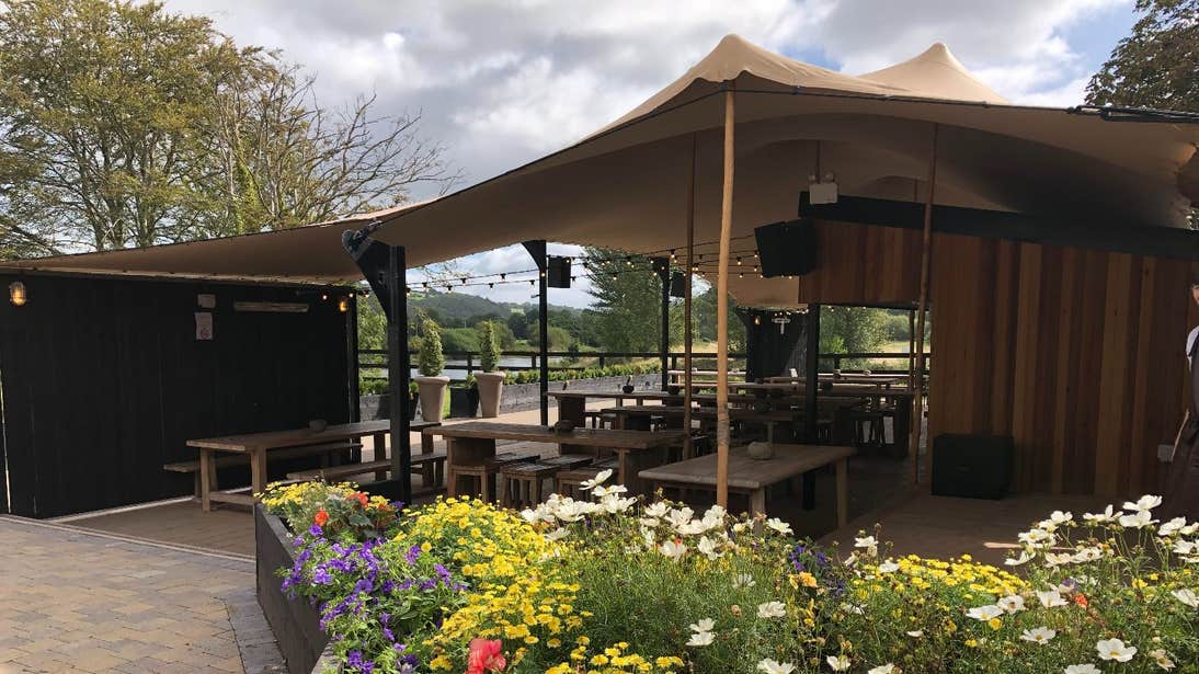 A large outdoor marquee surrounded by flowers at The Anglers, Carrigrohane, Cork