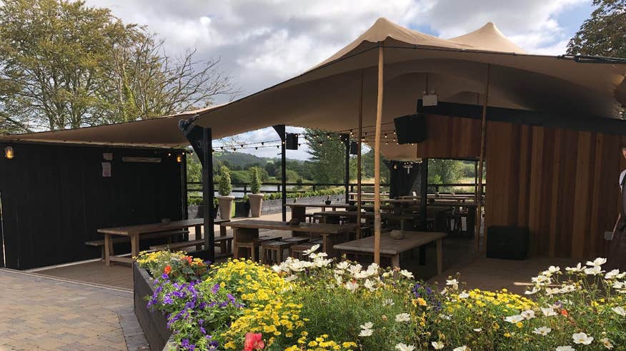 A large outdoor marquee surrounded by flowers at The Anglers, Carrigrohane, Cork