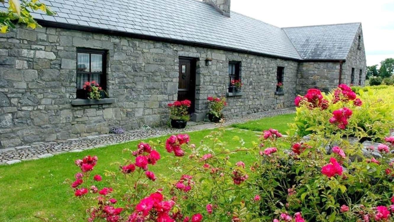 Stone house with pink flower by the door and in the garden in front