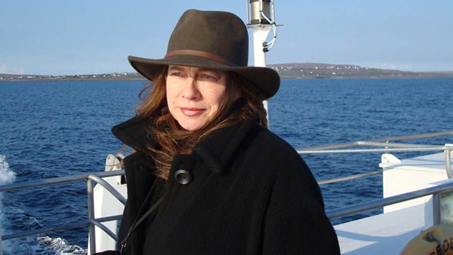 A lady with a hat on a ferry looking out to sea