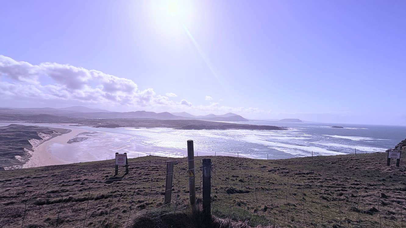 View over a field onto a beach under a sunny sky