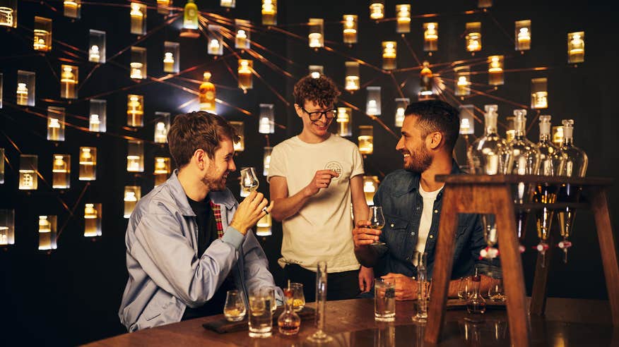 Three men enjoy a glass of whiskey inside  Roe & Co Whiskey.