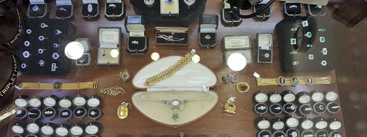 Large display of jewellery mainly rings and in centre gold bracelet and silver neckpiece