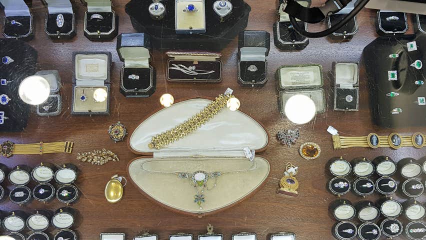 Large display of jewellery mainly rings and in centre gold bracelet and silver neckpiece