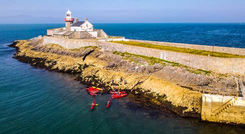 Aerial view of a group of kayakers near a lighthouse