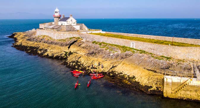 Aerial view of a group of kayakers near a lighthouse