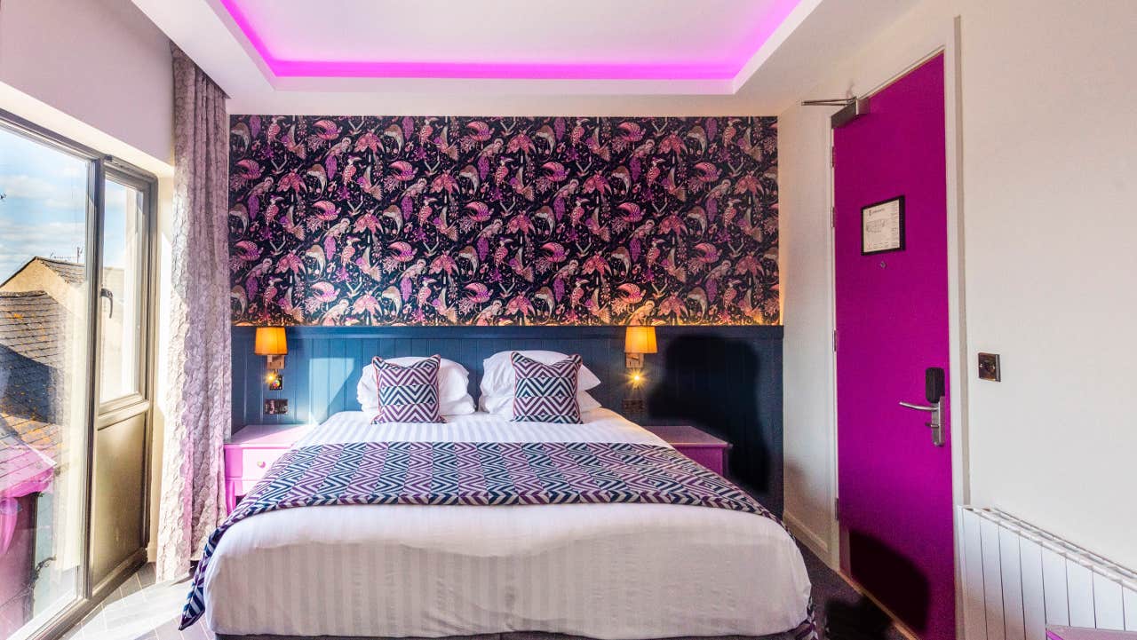 Double bedroom with white and purple sheets