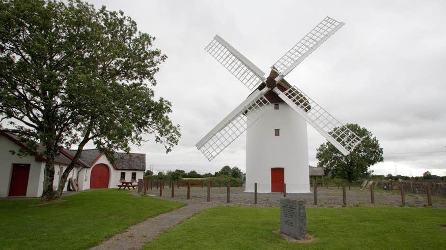 The large white Elphin Windmill with a red door beside a tree in Roscommon