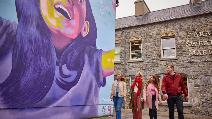 People walking past a mural in Galway city