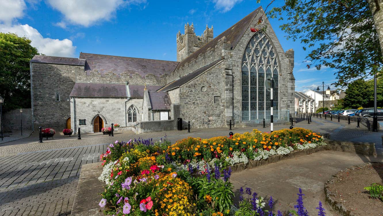 Exterior of The Black Abbey Kilkenny City showing the Rosary Window from the outside with flower beds to the front of the picture