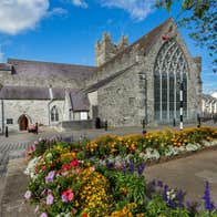 Exterior of The Black Abbey Kilkenny City showing the Rosary Window from the outside with flower beds to the front of the picture