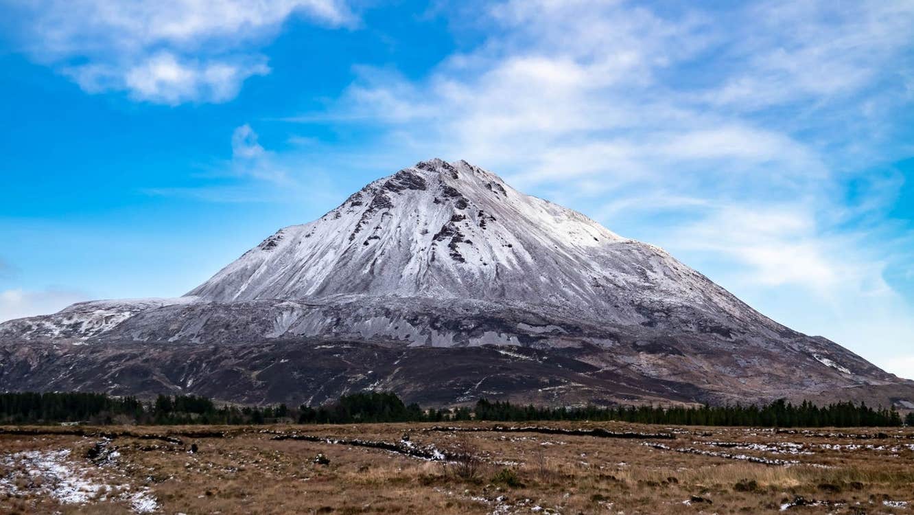 A mountain with a pale coloured peak and dark bogland at the foot
